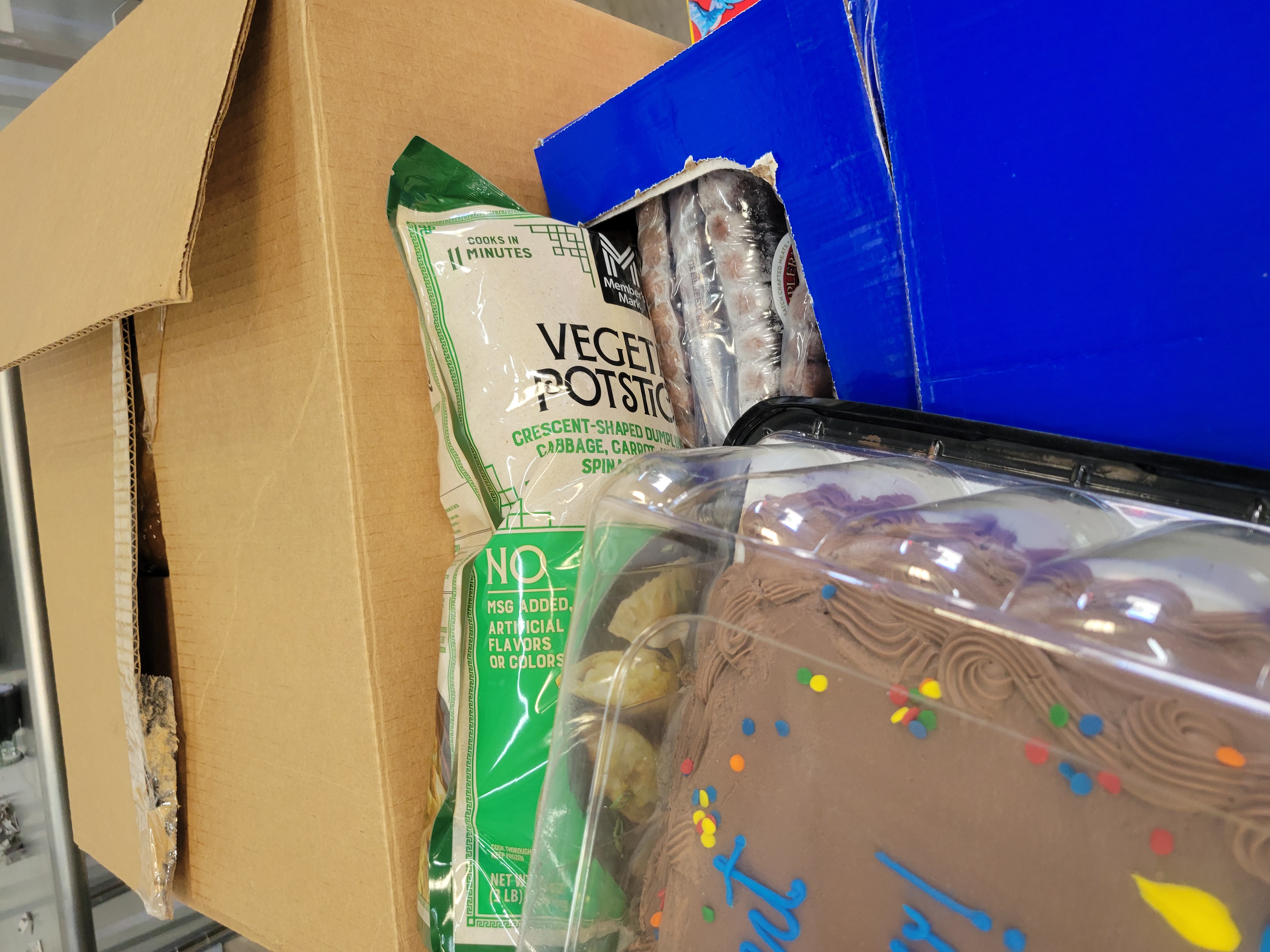 Chocolate sheet cake and package of vegetable potsticker on boxes of food.